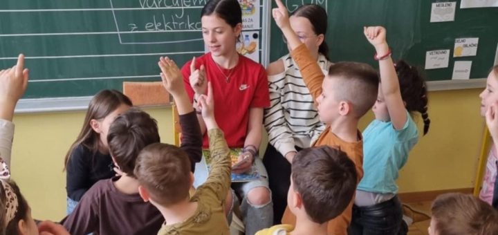 Učenci na bralnem petku dvigujejo roke, da bi povedali rešitev uganke.