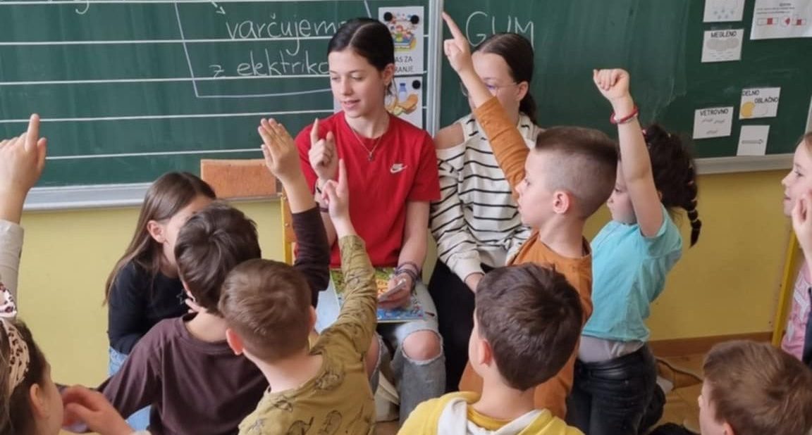 Učenci na bralnem petku dvigujejo roke, da bi povedali rešitev uganke.